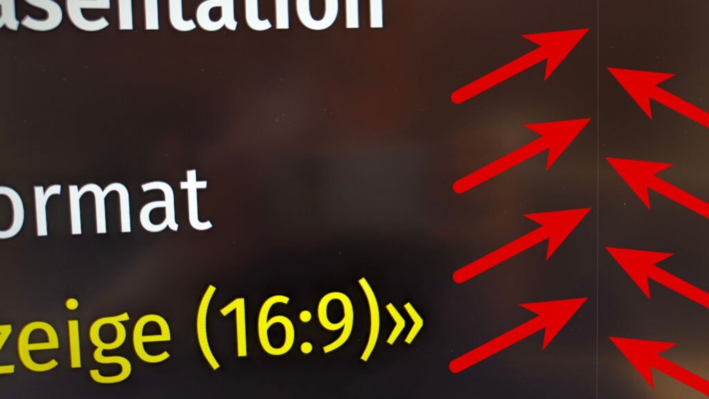 Foto des Bildschirms, auf dem eine LibreOffice-Folie mit dunklem Hintergrund und eine feine, vertikale weisse Linie zu sehen ist. Diese Linie ist mit roten Pfeilen markiert